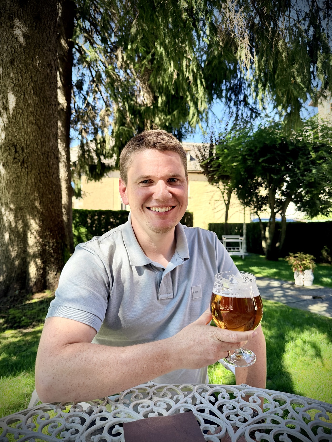 Rainer lächelt mit einem Bierglas an einem Gartentisch.